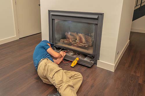 Service technician working on a gas fireplace inside of a residential home