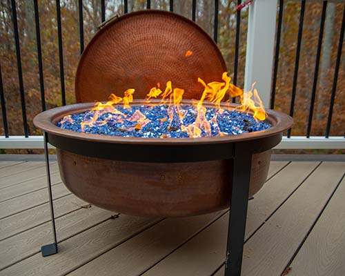 Lit copper Fire Pit on backyard porch, with blue crystals.